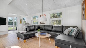 Una sala de estar moderna con un sofá modular, una mesa de centro y amplias ventanas que ofrecen vistas al exterior.