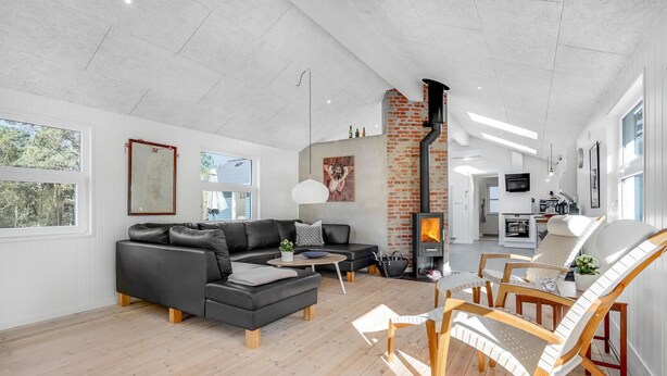 Una sala de estar amplia con chimenea, un comedor con mesa y sillas de madera, y una cocina al fondo.