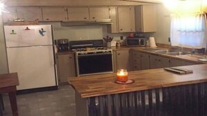 A kitchen with a wooden island, a refrigerator, a stove, and a microwave.