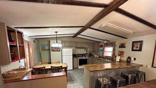 A kitchen with a central island, bar stools, and a dining area with a table and chairs.
