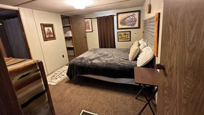 A bedroom with a bed, a chair, a wardrobe, and a small rug.
