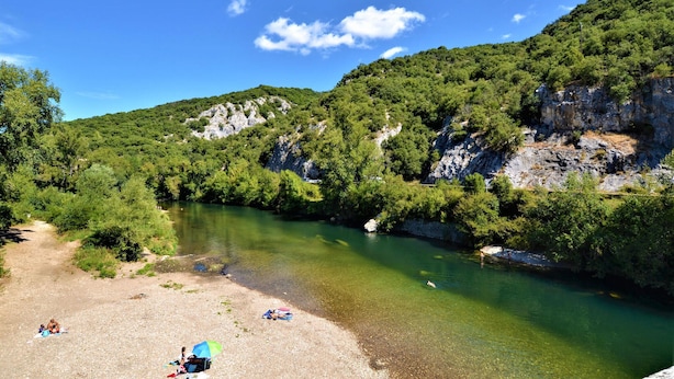 Un fiume circondato da una vegetazione rigogliosa e imponenti pareti rocciose.