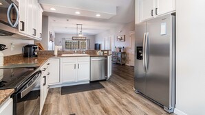 Una cocina moderna con armarios blancos, electrodomésticos de acero inoxidable y suelo de madera.