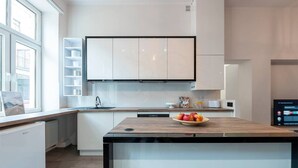 Una cocina moderna con armarios blancos, encimera de madera y lavavajillas integrado.