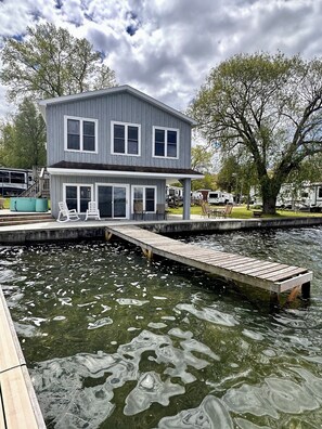 A two-story house with a dock extending into a body of water. - Lakefront Cottage with Stunning Views. Boat available to rent with cottage! (Castile)