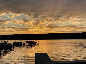 Un tramonto sul lago calmo, con barche ormeggiate al pontile.