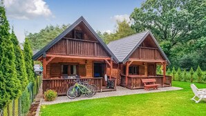 Een houten vakantiehuisje met veranda, een fiets en een gazon.