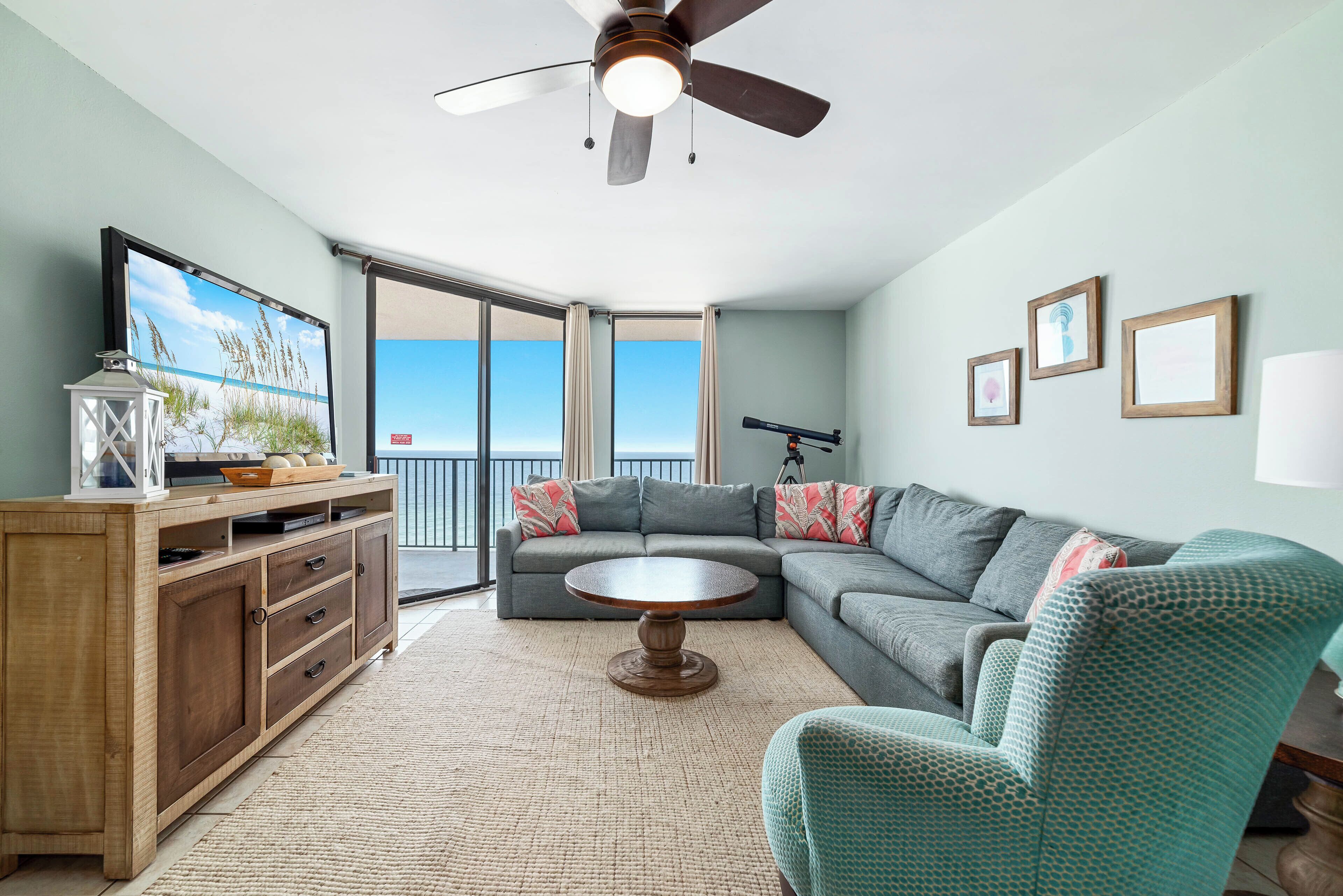 A living room with a sectional sofa, a wooden cabinet, a round coffee table, and a ceiling fan.