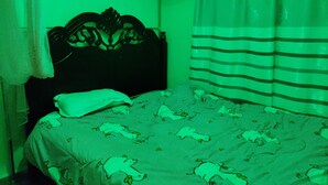 Une chambre avec un lit, une tête de lit et une fenêtre avec des rideaux.