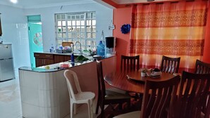 Une cuisine dotée d’un îlot central, de chaises blanches et d’une table à manger avec des chaises en bois.