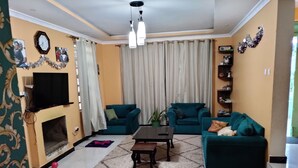 Un salon avec des canapés de couleur turquoise, une cheminée, une horloge et un lustre.
