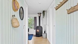 A narrow hallway with a wooden floor, a black wood stove, and a hanging basket.