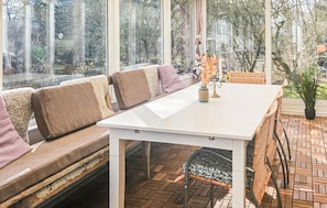 Een zonnige kamer met een witte tafel, een comfortabele bank en een potplant.