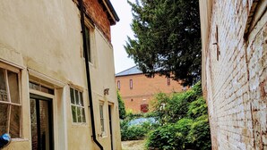 A narrow alleyway with a stone pathway, a green door, and a brick building in the background. - 4bedhouse/leominster/hiking/castles/sleeps7/wifi (Leominster)