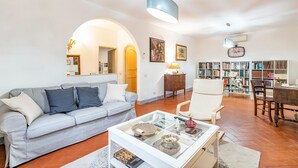 Una sala de estar con sofá, sillones, una mesa de centro, una estantería y un comedor.