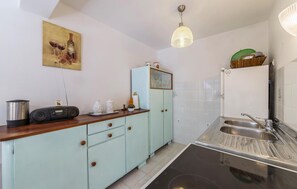 Een kleine keuken met een spoelbak, een radio en een kast.