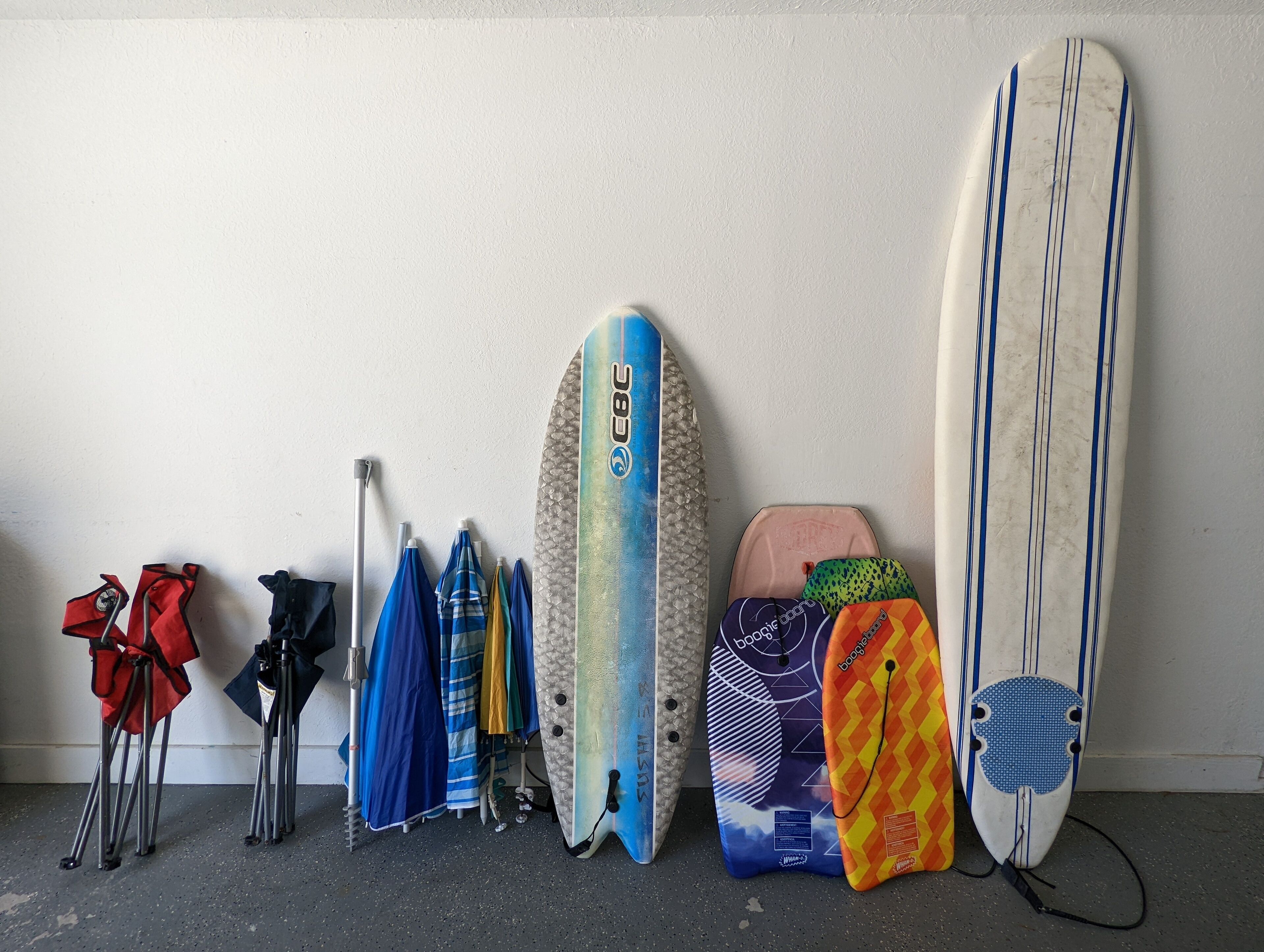 Varias tablas de surf y una tabla de remo apoyadas contra una pared.