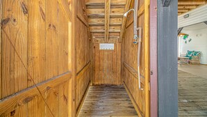 Un étroit couloir en bois, avec une pancarte indiquant « PLAGE », et un espace douche équipé d’un tuyau en métal.