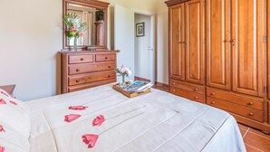 A bedroom with a bed, a dresser, a vanity, and a wardrobe.