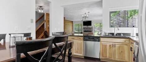 A modern kitchen with wooden cabinets, a central island, and a large window providing natural light.