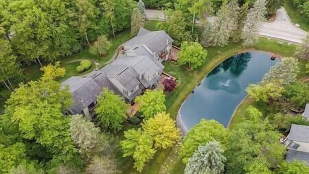 An aerial view of a house surrounded by lush greenery and a swimming pool.