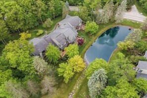 Vista aérea de una casa rodeada de exuberante vegetación y una piscina.