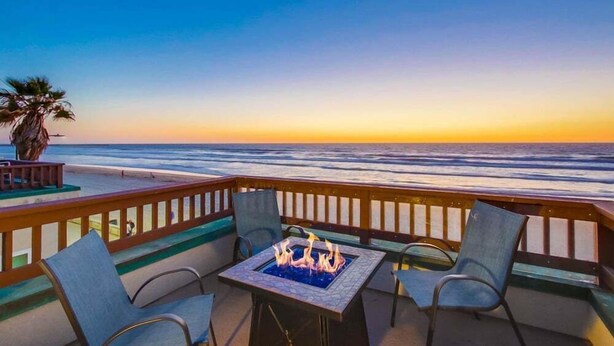 A balcony with a fire pit, chairs, and a view of the ocean at sunset. - Ocean Front * Top Level + Sky Deck * Dog OK (San Diego)