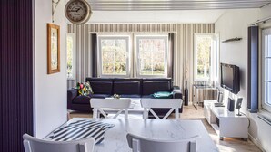 Una sala moderna con sofá, mesa de comedor, sillas y televisor.