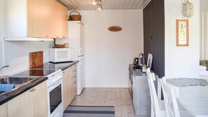 Cocina compacta con microondas, horno y lavabo. Un pequeño comedor con mesa y sillas.