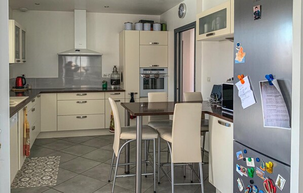 A compact kitchen with a dining area, including a refrigerator with magnets, a stove, and cabinets.