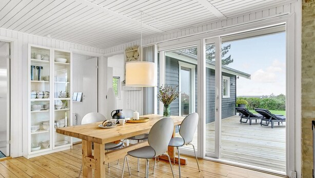 A modern dining area with a wooden table, white chairs, and a glass cabinet with dishes.