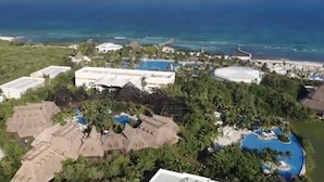 Vista aérea de un resort con varias piscinas, un edificio grande y una zona de playa.