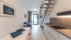 A modern apartment with a kitchen, dining area, and a staircase leading to an upper floor. - 2 bedroom beach front home in Okrug Gornji (Okrug Gornji)