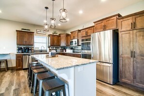 A modern kitchen with wooden cabinets, stainless steel appliances, and a central island with bar stools. - Table Rock Lake View! Two Community Pools! (Branson)