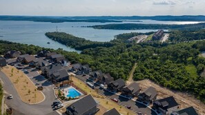 An aerial view of a residential area with houses, a swimming pool, and a large body of water in the background. - Table Rock Lake View! Two Community Pools! (Branson)