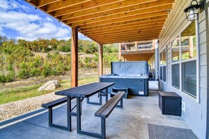 An outdoor patio area with a hot tub, wooden tables, and benches. - Table Rock Lake View! Two Community Pools! (Branson)