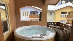 A hot tub with wooden seating and a view of a house through a window. - Fantastic location; 2 bdrm w/ private hot tub (Sun Peaks)