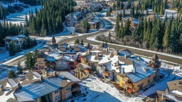 An aerial view of a snow-covered residential area with houses and a church. - Fantastic location; 2 bdrm w/ private hot tub (Sun Peaks)