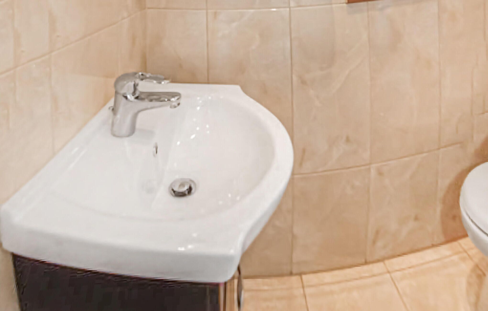 Un bagno con un lavandino bianco, uno specchio e un water.