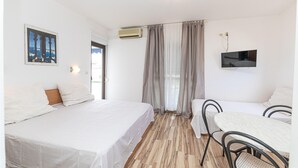 Une chambre d’hôtel avec un lit, un bureau, une chaise, une tél évision et une fenêtre avec des rideaux.