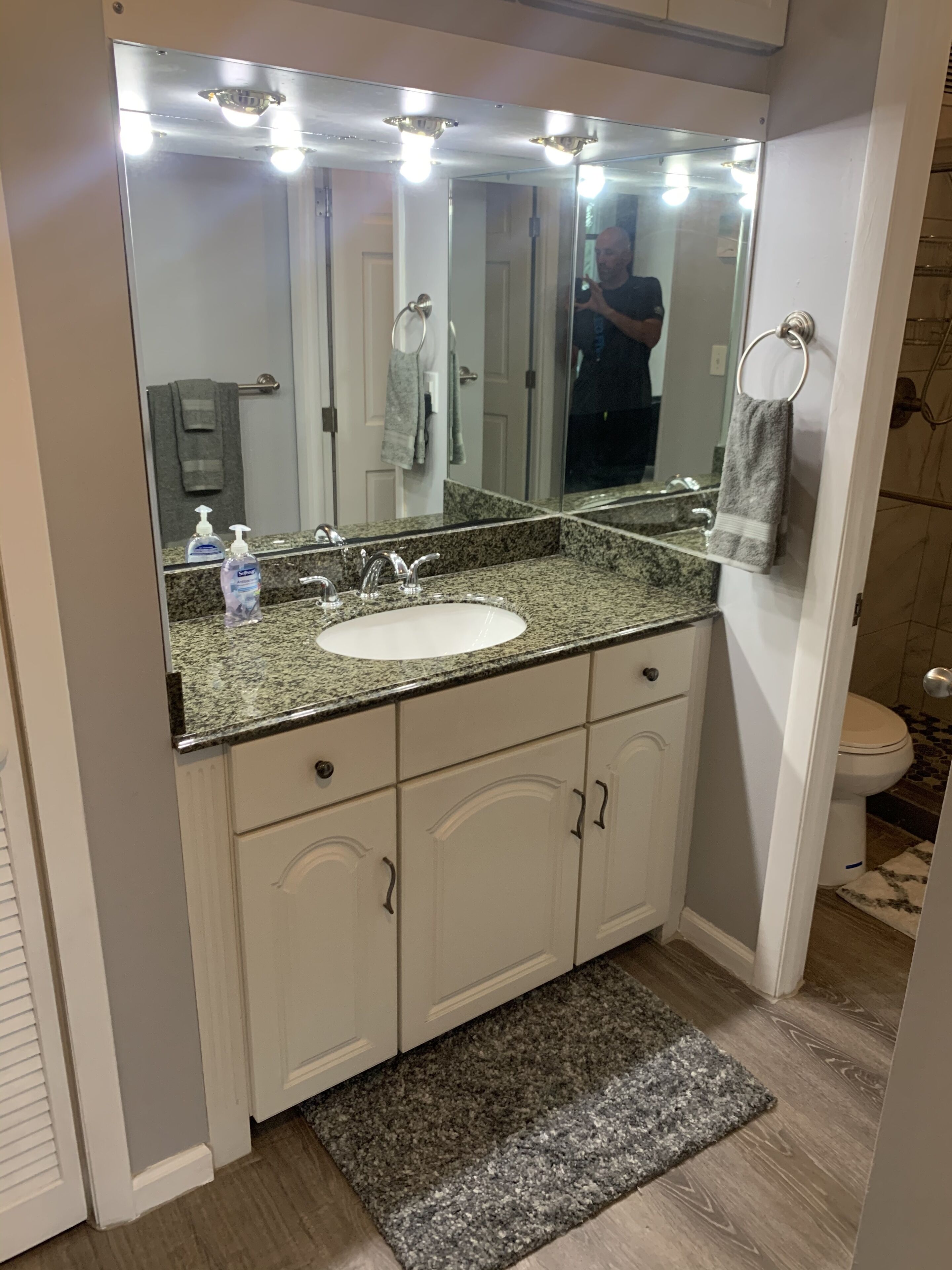 A bathroom with a large mirror, a sink, and a toilet.