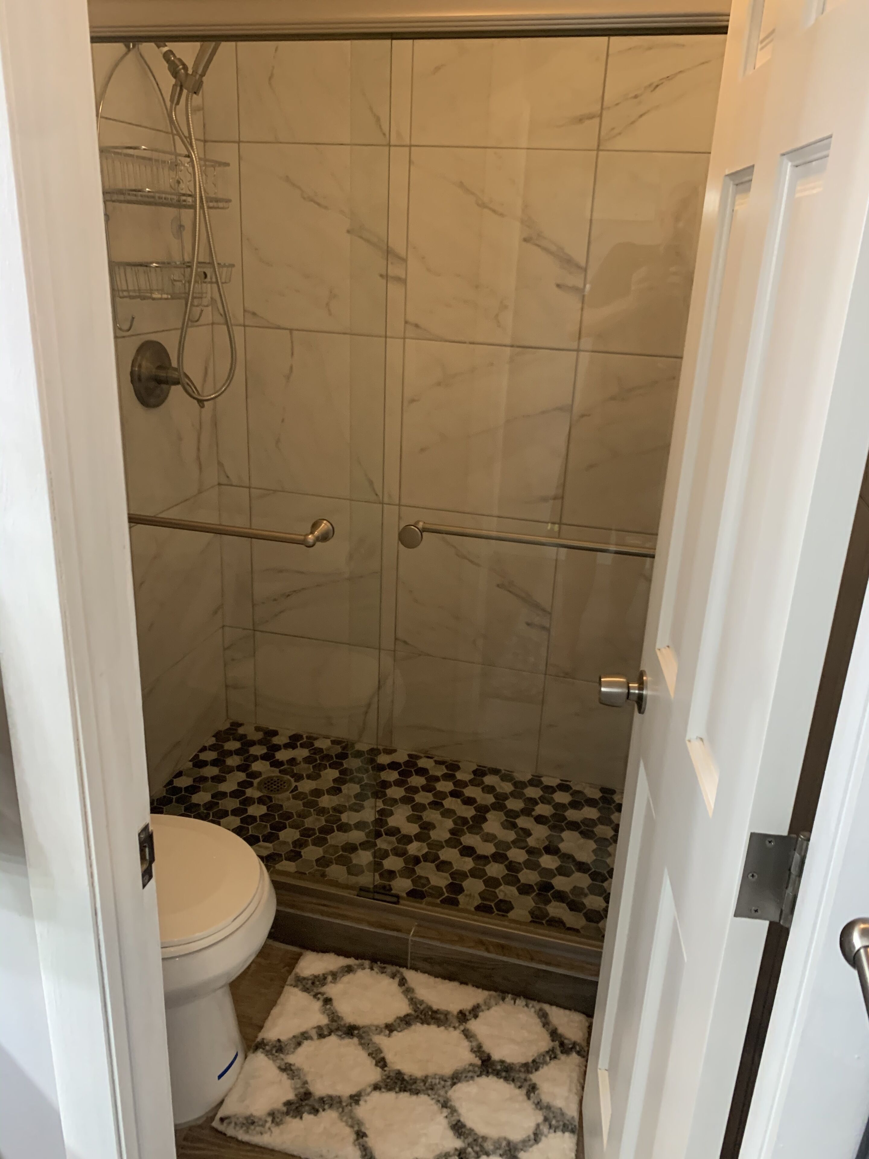 Une salle de bain avec une douche, des toilettes et un carrelage décoratif.
