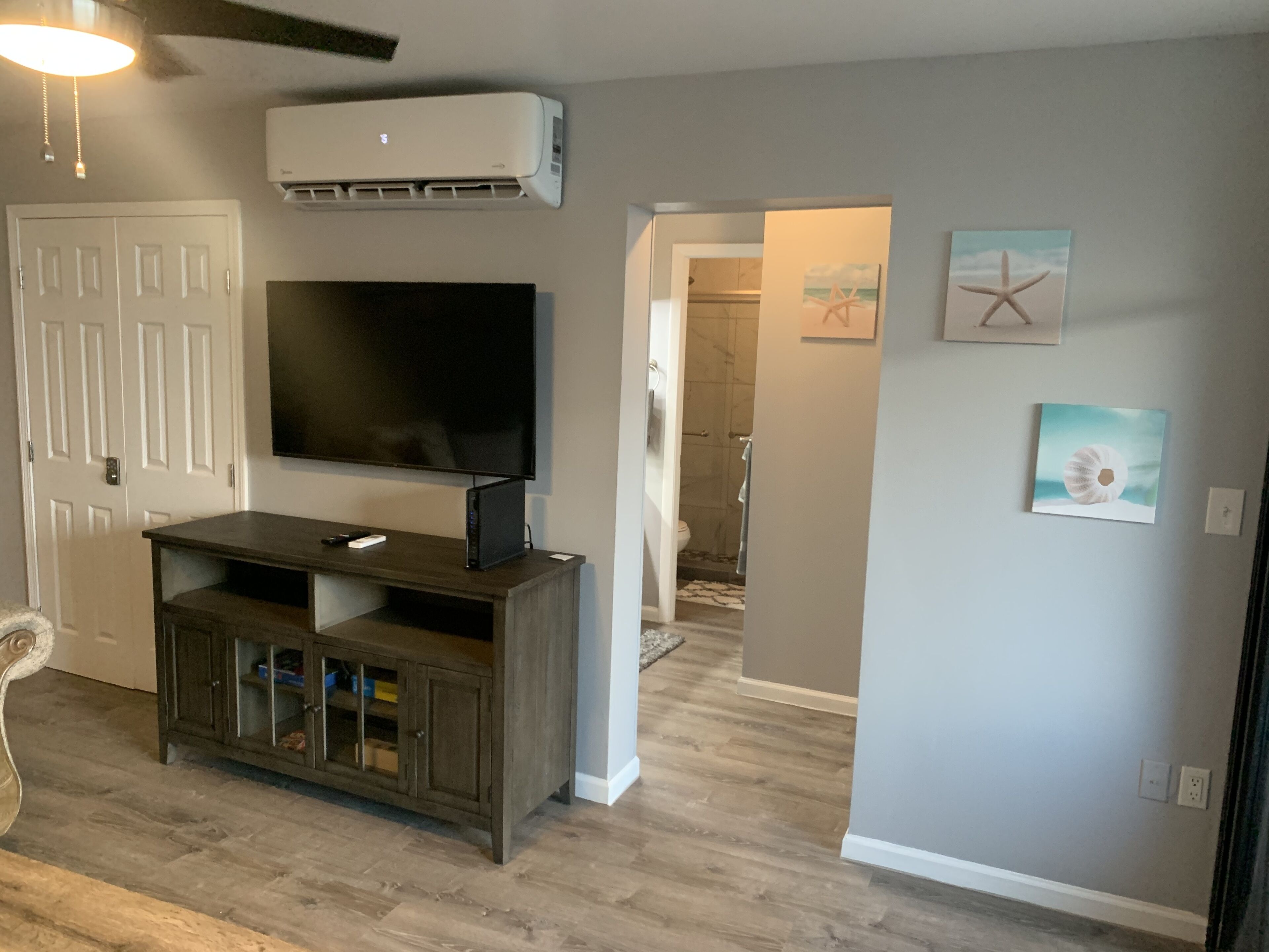 A living room with a TV, entertainment unit, and artwork on the walls.