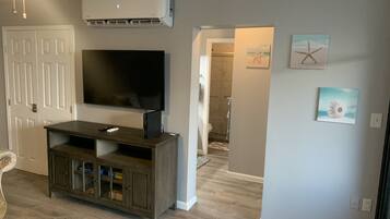 A living room with a TV, entertainment unit, and artwork on the walls.