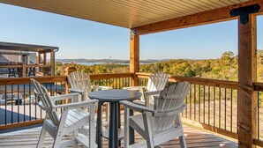 A wooden deck with white chairs and a table, overlooking a scenic landscape with hills and a body of water. - Gorgeous Table Rock Lake View! Hot Tub, Pool! (Branson)