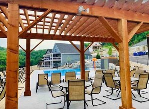 A covered outdoor seating area with chairs and a pool. - Gorgeous Table Rock Lake View! Hot Tub, Pool! (Branson)
