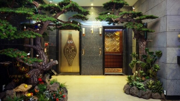 Un vestíbulo con entrada de estilo japonés tradicional, que incluye una puerta torii y una cascada.