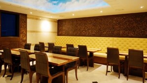 Un salón de conferencias con techo alto, una pantalla grande y una zona de estar con un banco acolchado amarillo.