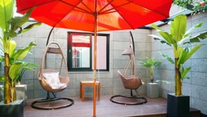 Un patio con dos sillas mecedoras, una mesa y una sombrilla.