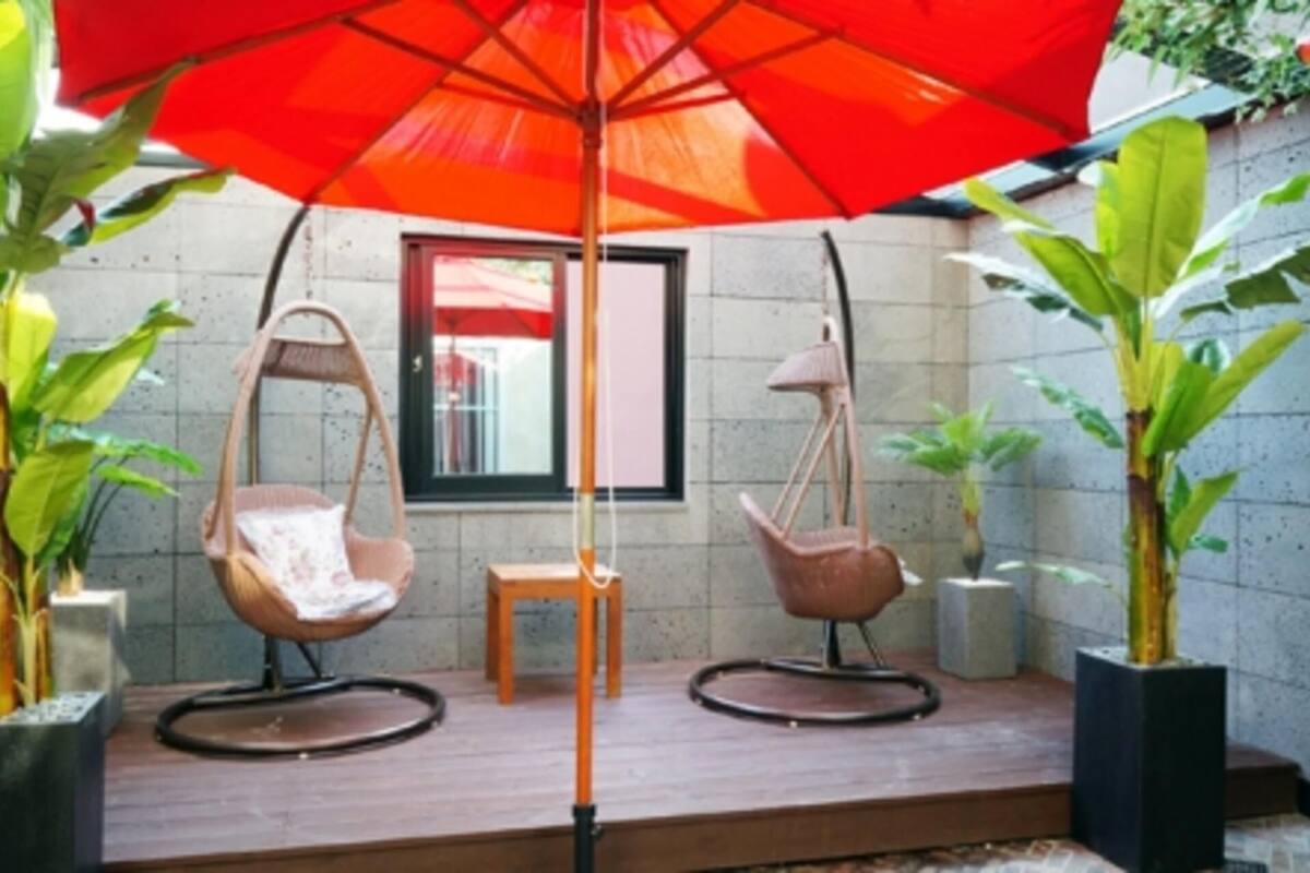 A patio with two swing chairs, a table, and an umbrella.